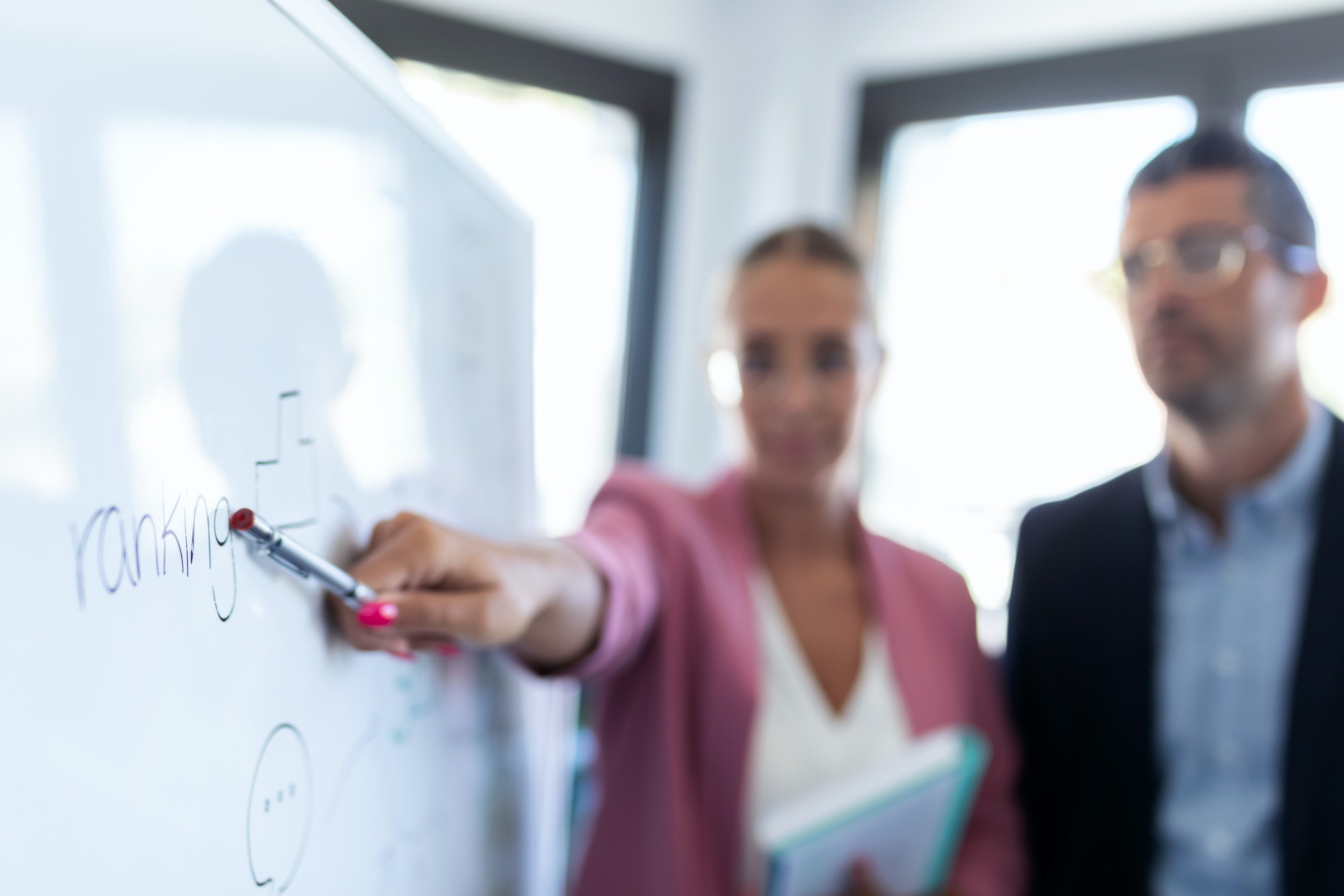 young businesswoman pointing at white blackboard and explain a project to her colleagues young businesswoman pointing at white blackboard and explain a project to her colleagues